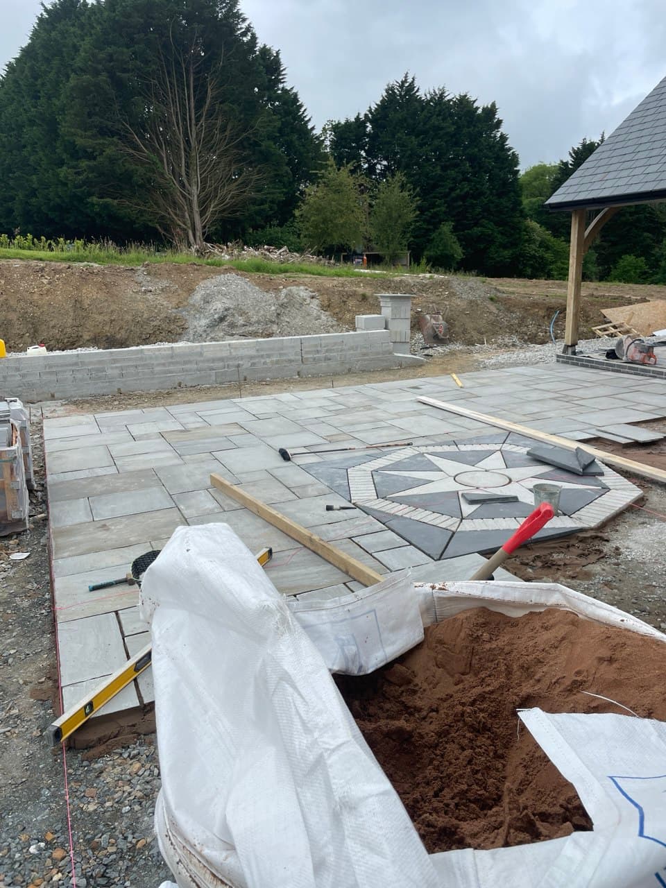 Close-up of decorative compass rose stone feature being laid within natural stone patio at new build property