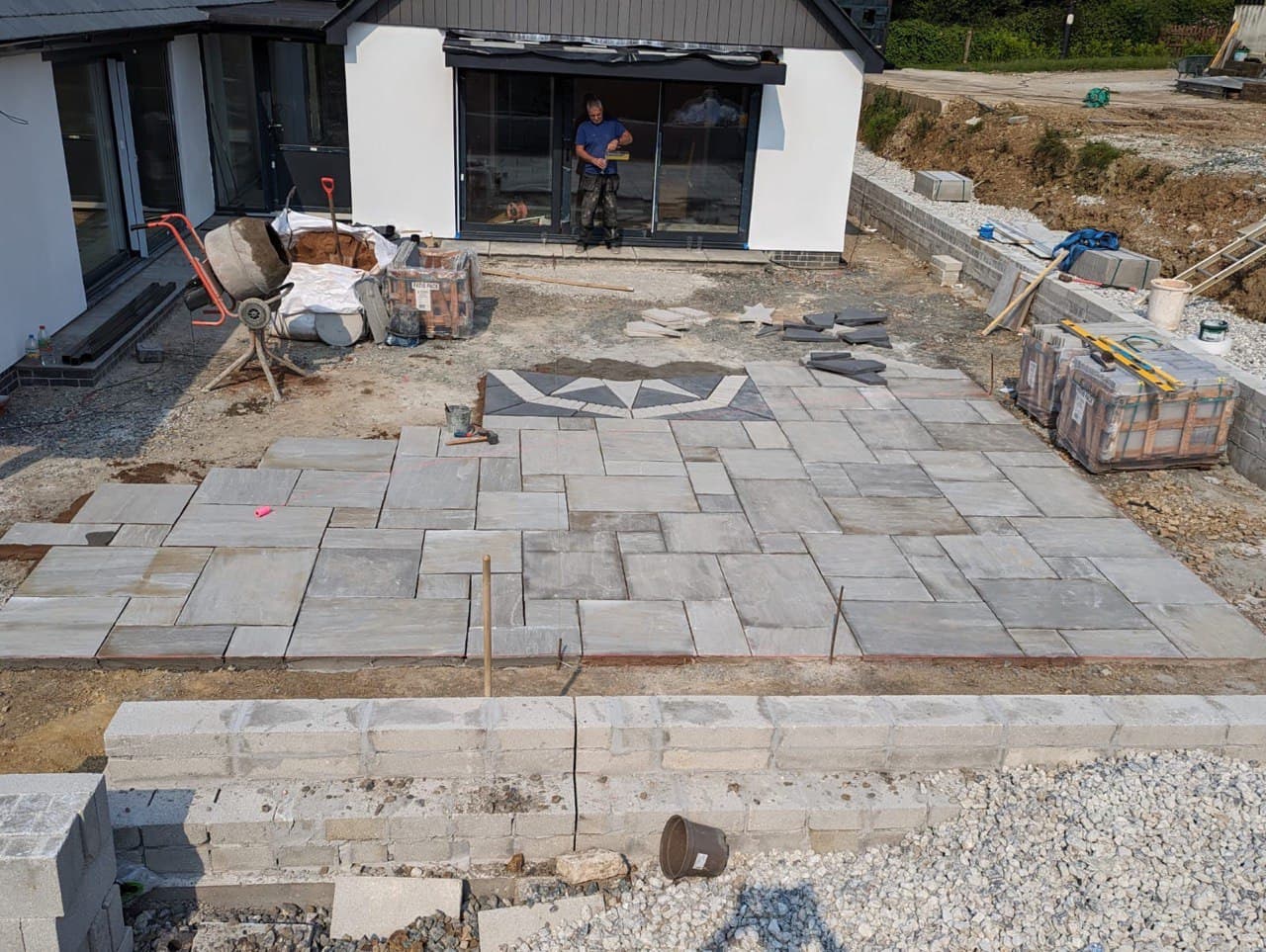 Elevated view of natural stone patio under construction with compass rose centrepiece at Thornbury Devon new build